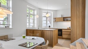A modern kitchen with wooden cabinets, a central island, and a dining area with a table and chairs.