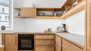A compact kitchen with wooden cabinetry, a built-in oven, and a coffee maker on the countertop.
