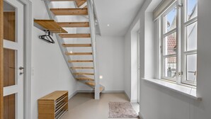 A modern staircase with wooden beams, a built-in bench, and a view of the outside through large windows.