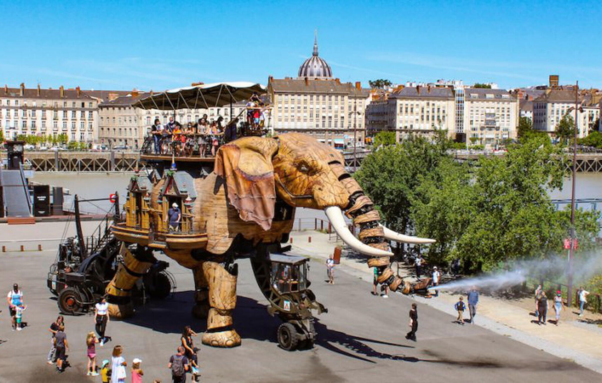 Un'imponente statua di elefante con una piattaforma e persone intorno.