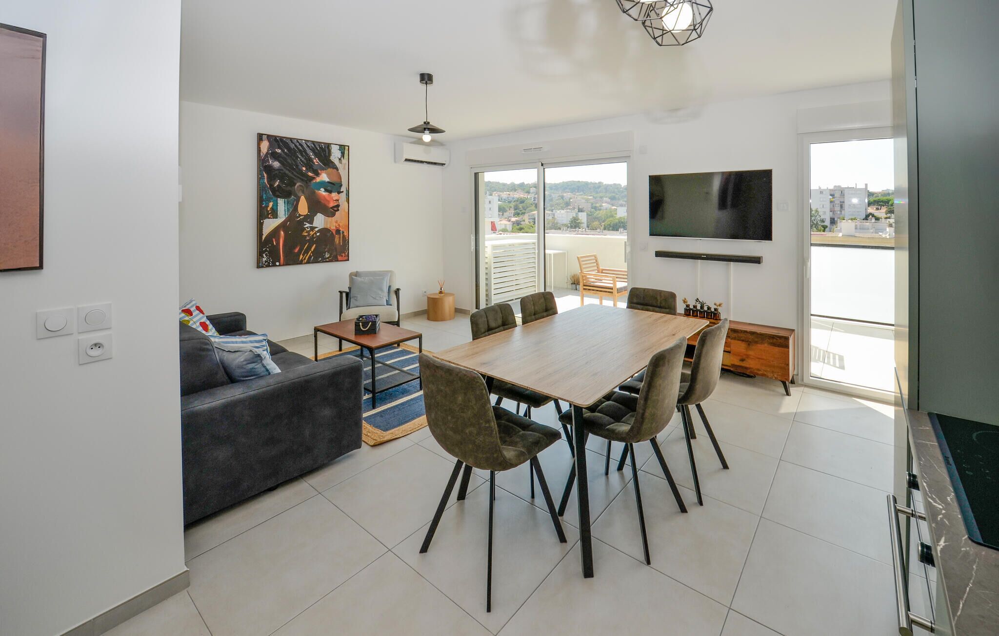 A modern living room with a dining area, a sofa, a coffee table, and a TV mounted on the wall.