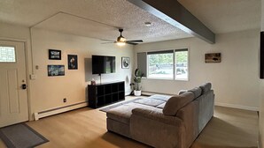 A spacious living room with a large sectional sofa, a ceiling fan, and a television. - Beautiful Alaskan 2 Bedroom (Anchorage)