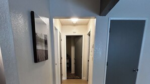 A hallway with a wooden floor, white walls, and a door on the right. - Beautiful Alaskan 2 Bedroom (Anchorage)