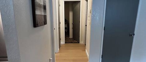 A hallway with a wooden floor, white walls, and a door on the right.