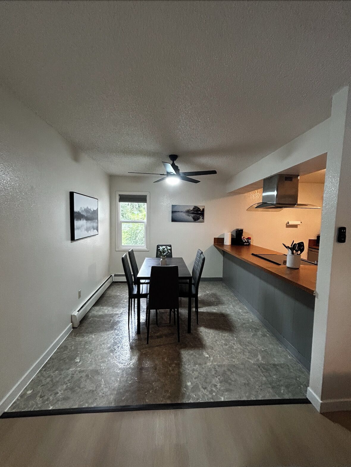 A compact kitchen with a dining area, a ceiling fan, and a window.