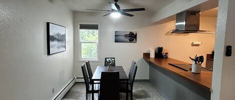 A compact kitchen with a dining area, a ceiling fan, and a window.