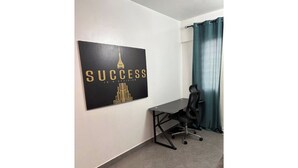 A room with a desk, a chair, a black and gold motivational poster, and a teal curtain. - HideHaus Haven (Kumasi)