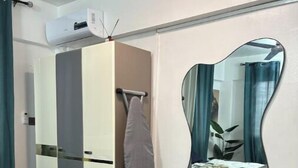 A bedroom with a bed, a wardrobe, a mirror, and an air conditioning unit. - HideHaus Haven (Kumasi)