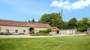 A large building with a tiled roof, an arched entrance, and a grassy lawn in front. - Beautiful home in Monthenault with WiFi (Monthenault)