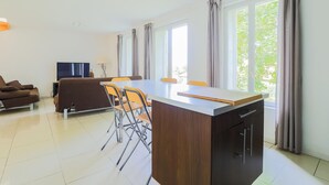 A modern living room with a sofa, a dining table with chairs, a TV, and large windows with curtains. - Beautiful home in Monthenault with WiFi (Monthenault)