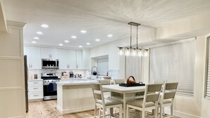 A modern kitchen with white cabinetry, a central island with seating, and a chandelier. - Gorgeous Executive Home (Draper)