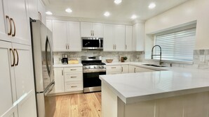 A modern kitchen with white cabinetry, stainless steel appliances, and a wooden floor. - Gorgeous Executive Home (Draper)