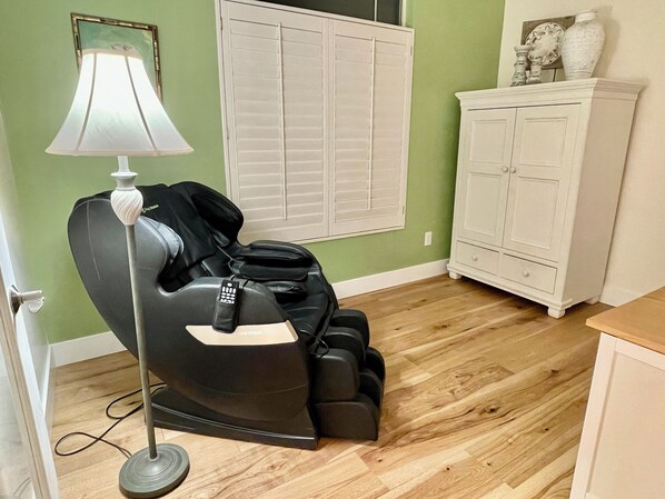 A massage chair in a room with green walls, a white cabinet, and a wooden floor.