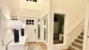 A hallway with a white door, a white console table with a lamp, a blue vase, and a wooden floor. - Gorgeous Executive Home (Draper)