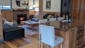 A cozy living room with a fireplace, a dining area with a wooden island, and a kitchen with wooden cabinets.