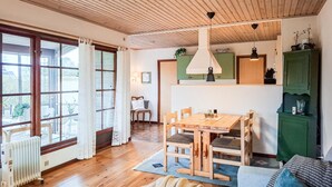 A cozy room with a wooden floor, a dining table with chairs, a green cabinet, and a window with curtains. - Beautiful home in Otterup with WiFi (Otterup)