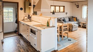 A modern kitchen with a built-in oven, a sink, and a dining area with a table and chairs. - Beautiful home in Otterup with WiFi (Otterup)