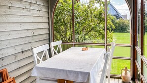 A wooden deck with a table and chairs, large windows with a view of a green field and trees. - Beautiful home in Otterup with WiFi (Otterup)