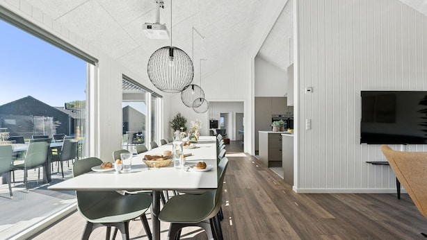 A modern dining area with a long table, chairs, and pendant lighting. - Cozy home in Bogense with sauna (Bogense)