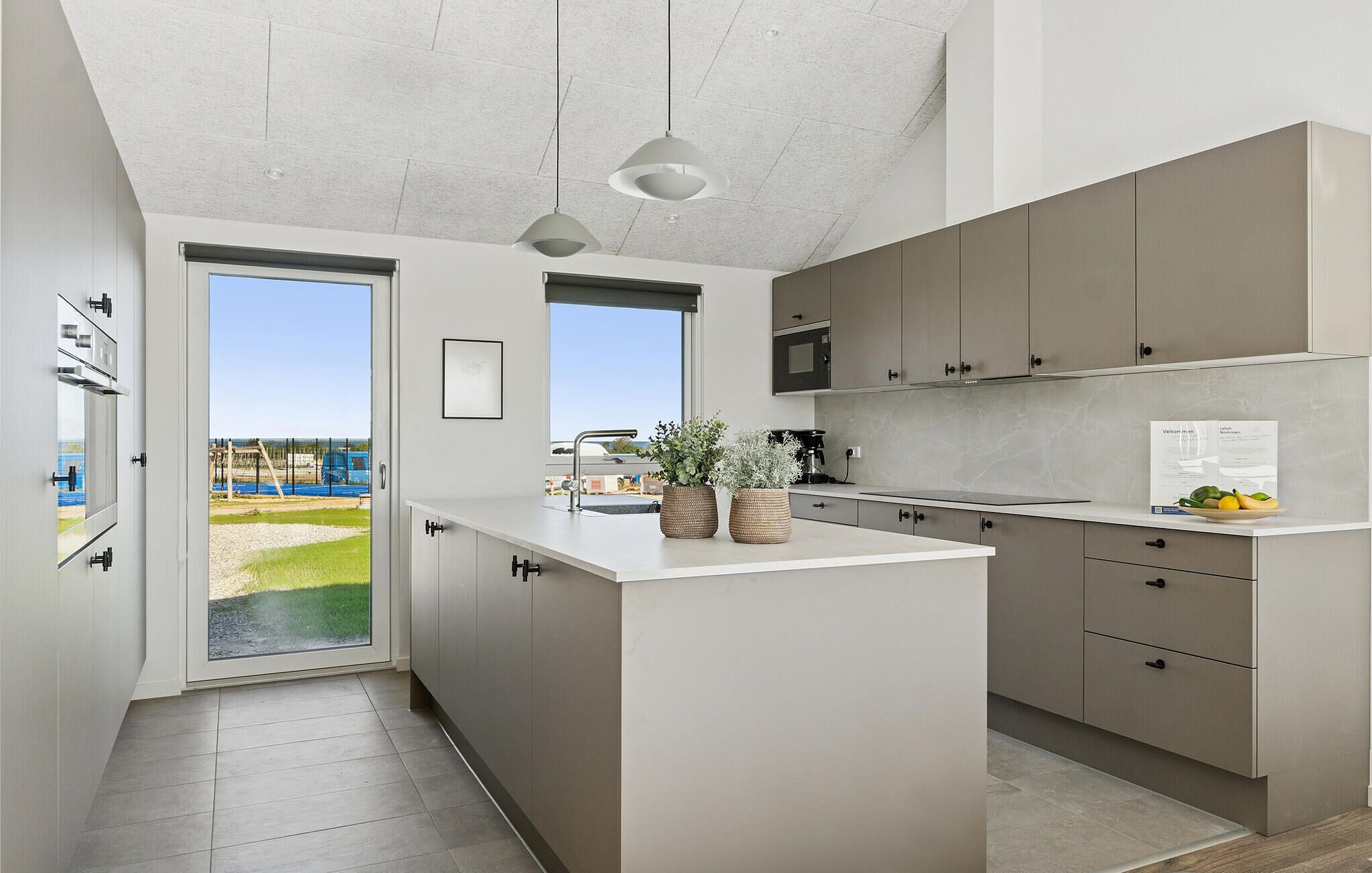 Una cucina moderna con un'isola grande, elettrodomestici integrati e vista su un giardino.