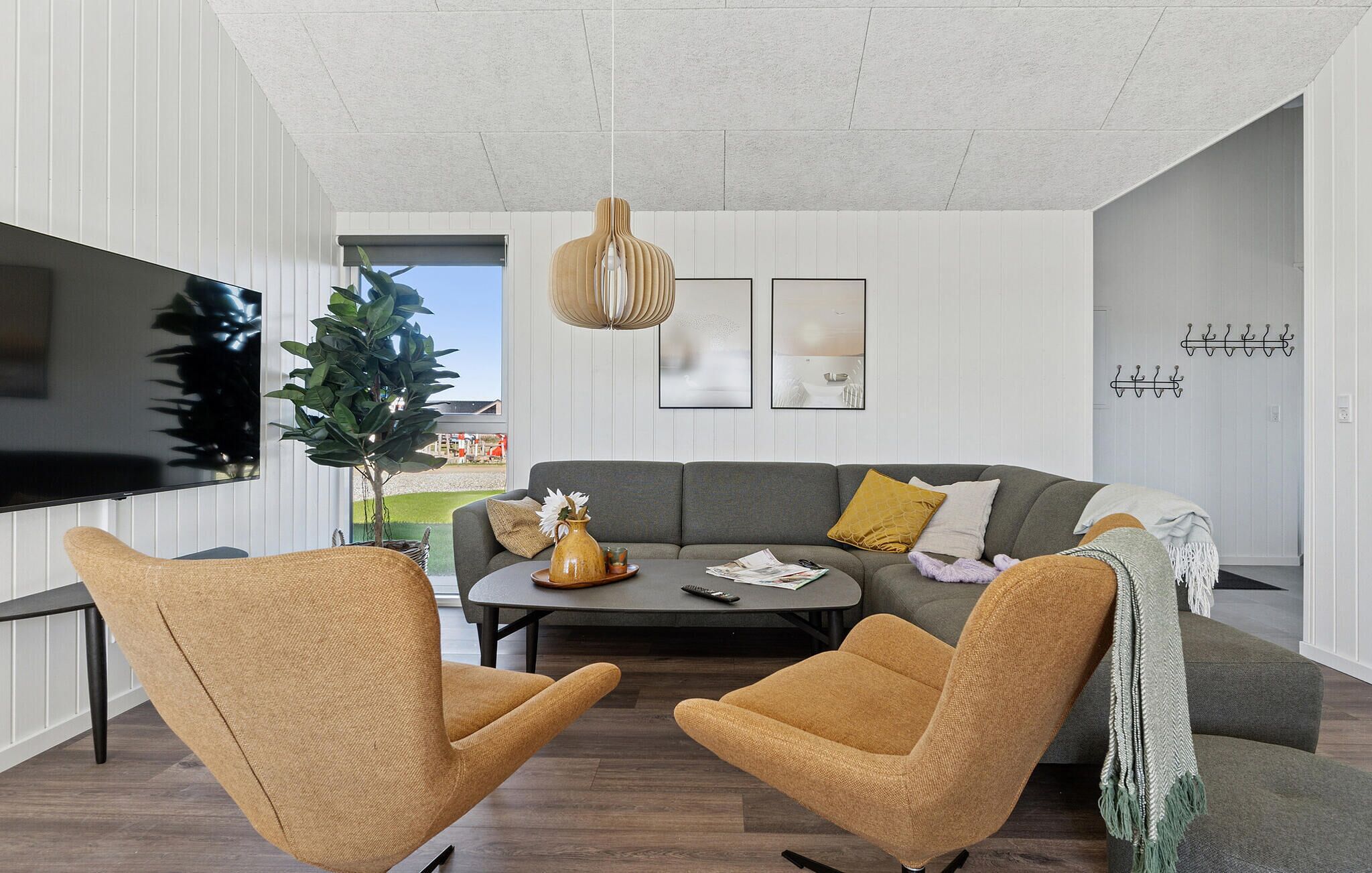 Un salon moderne avec un canapé gris, deux fauteuils, une table basse et un téléviseur.