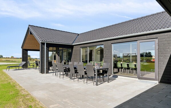 Un bâtiment moderne doté d’un patio comprenant un espace extérieur aménagé avec des sièges et une partie couverte.