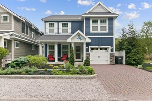 Ein zweistöckiges Haus mit Veranda, Garage und gepflegtem Garten.