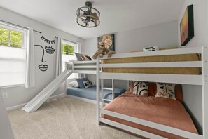 A bunk bed room with a staircase, a ceiling fan, and a window with curtains. - The BlueGrasshopper South Haven (South Haven)