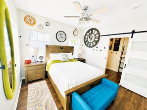 Ein Schlafzimmer mit einem Bett, Nachttischen, einem Deckenventilator und einer großen Uhr an der Wand.