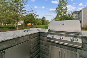 Eine Außenküche mit integriertem Grill, einer Stein Arbeitsplatte und einer Blumenkomposition.