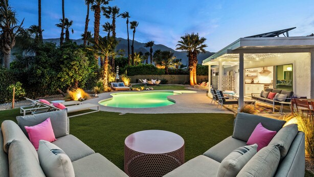 A modern outdoor living area with a pool, seating, and a covered patio.