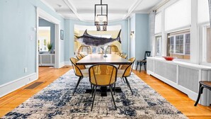 A dining area with a table and chairs, a hanging light fixture, and a window with a view. - Luxury 6BR Beach Home, Sleeps 16  – 1.5 Blks to Beach (Atlantic City)