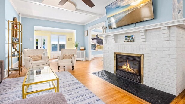 A living room with a fireplace, a ceiling fan, and a large TV on the wall. - Luxury 6BR Beach Home, Sleeps 16  – 1.5 Blks to Beach (Atlantic City)