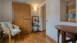 A room with a wooden wardrobe, a wicker chair, a wooden table, and a bookshelf. - 3 bedroom beautiful home in Montemarcello (Montemarcello)