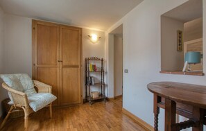 Quarto com guarda-roupa de madeira, uma cadeira de vime, mesa de madeira e uma estante.
