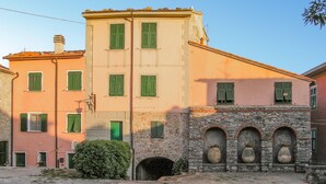 A building with multiple windows, a stone archway, and a small garden area. - 3 bedroom beautiful home in Montemarcello (Montemarcello)