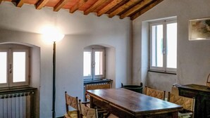 A dining room with a wooden table and chairs, a lamp, and windows. - 3 bedroom beautiful home in Montemarcello (Montemarcello)