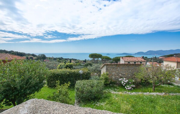 A coastal landscape with stone buildings, greenery, and a view of the sea.