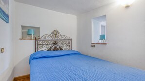 A bedroom with a bed, a wall-mounted mirror, and a shelf with a lamp. - 3 bedroom beautiful home in Montemarcello (Montemarcello)