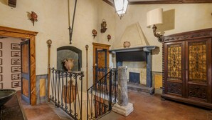 A room with a fireplace, a stone column, and a wooden cabinet with intricate designs.