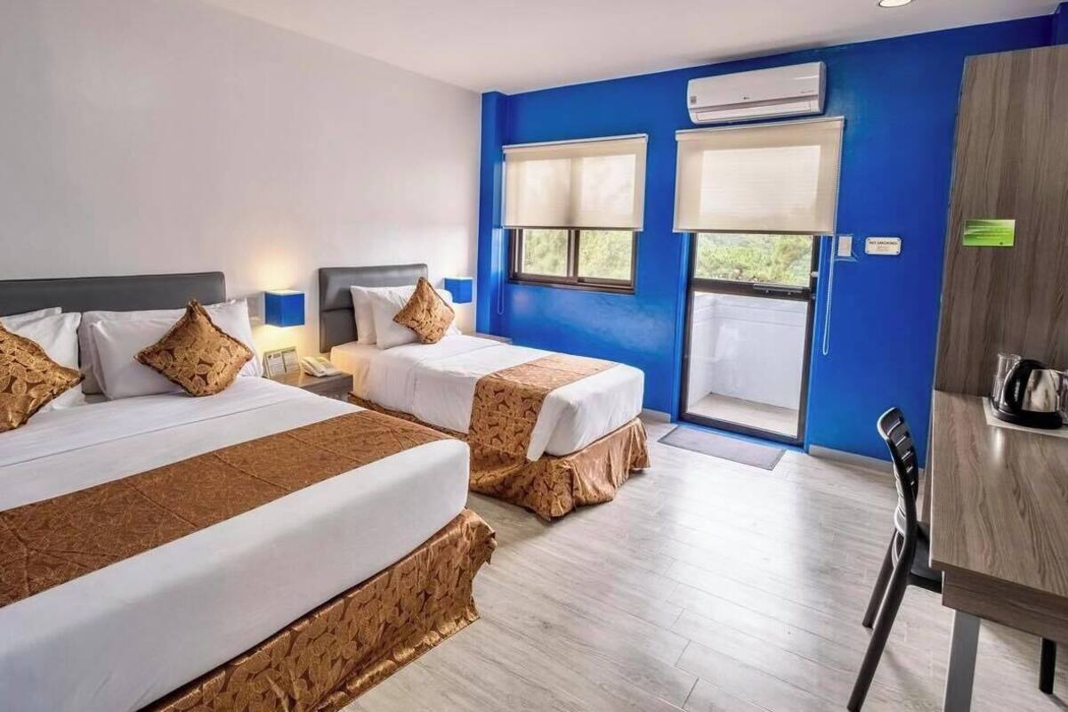 Een hotelkamer met twee bedden, een bureau en uitzicht op de omgeving.