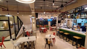 A modern cafe with tables and chairs, a bar area, and shelves with bottles. - Baguio LeFern Hotel (Baguio)