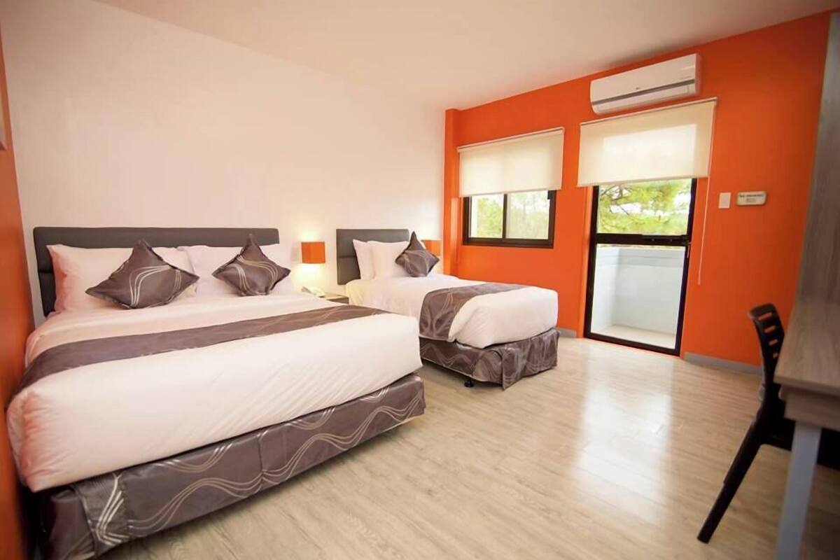 Een hotelkamer met twee bedden, een houten vloer en een oranje wand.