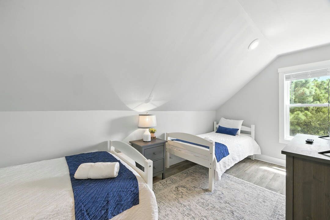 Une chambre avec deux lits simples, un bureau et une fenêtre.