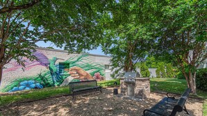 Un parque con un mural, una banca y una zona de barbacoa.