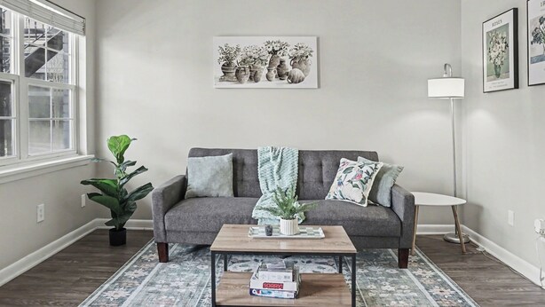 Una sala de estar con sofá, mesa de centro y plantas en macetas.