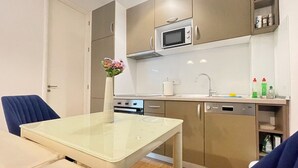 A compact kitchen with a microwave, oven, and sink. There is a dining table with chairs and a vase of flowers.
