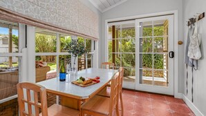 A dining area with a table and chairs, a bottle of wine, and a glass on the table.
