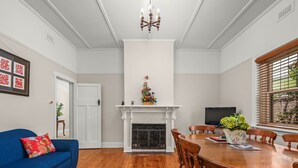 A dining room with a fireplace, a blue sofa, and a dining table with chairs.