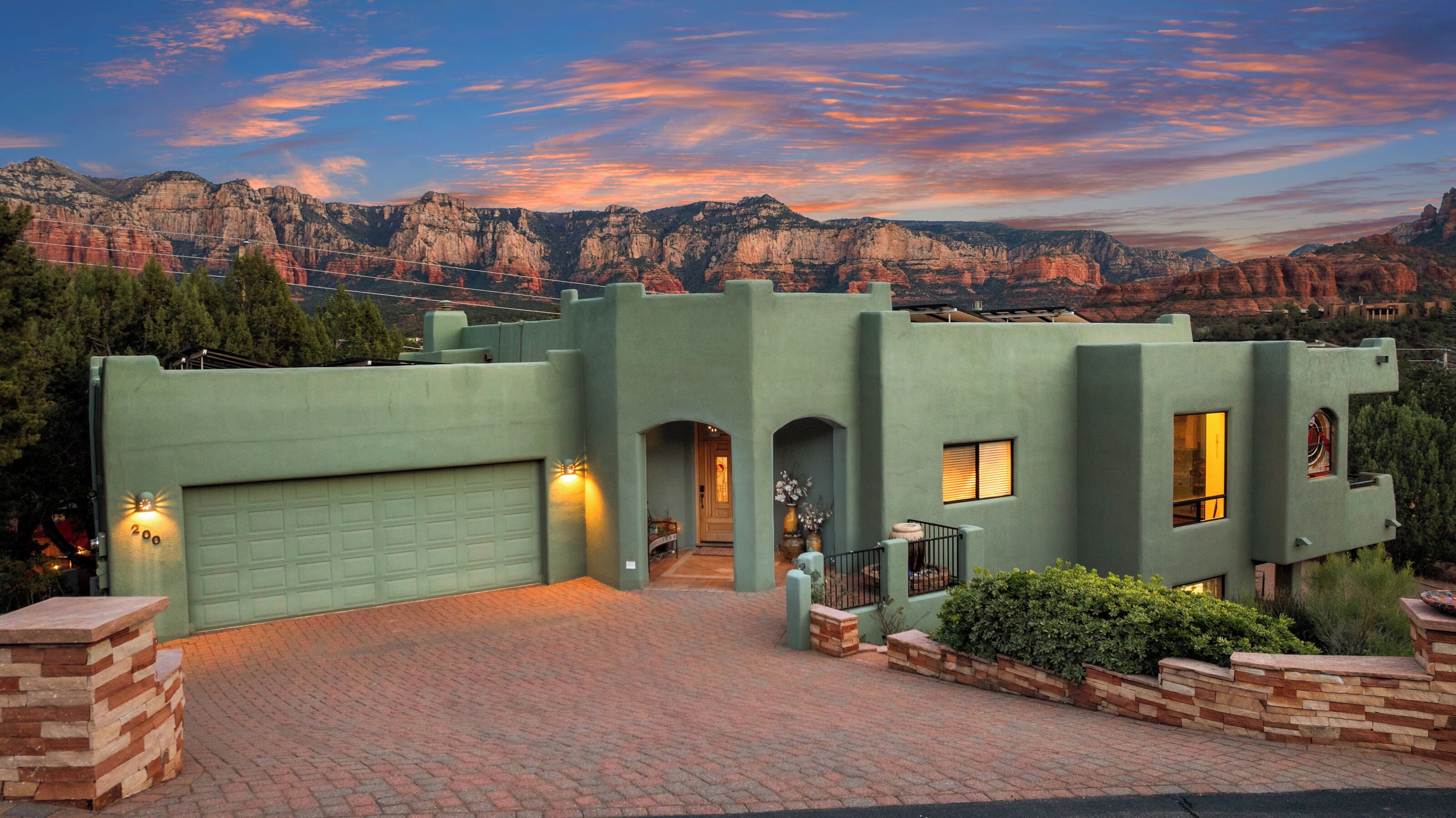 A modern house with a garage, a brick driveway, and a view of mountains.